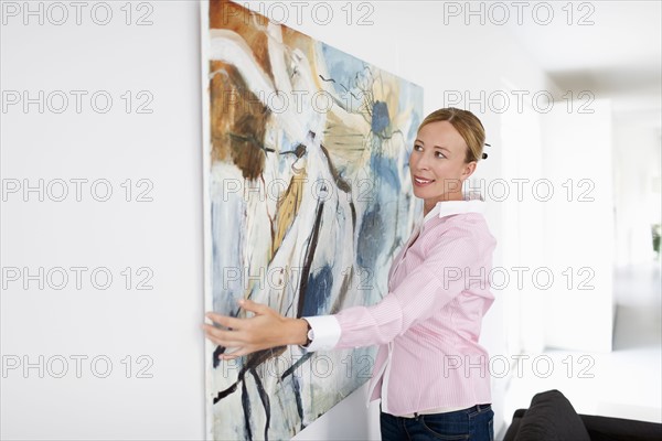 Woman hanging paintings indoors