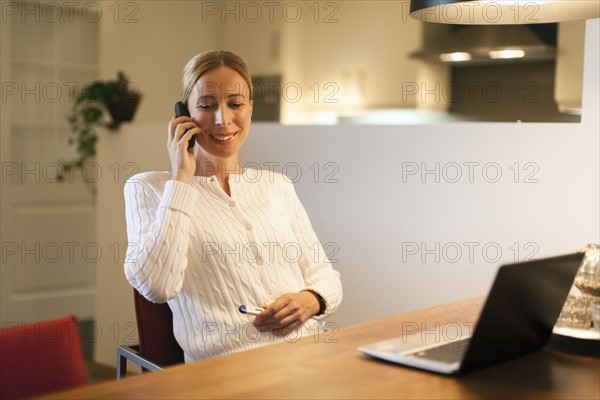 Woman using laptop and cell phone at home