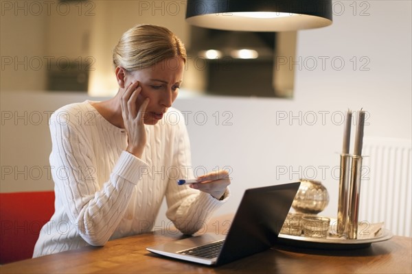 Woman using laptop and looking at pregnancy test