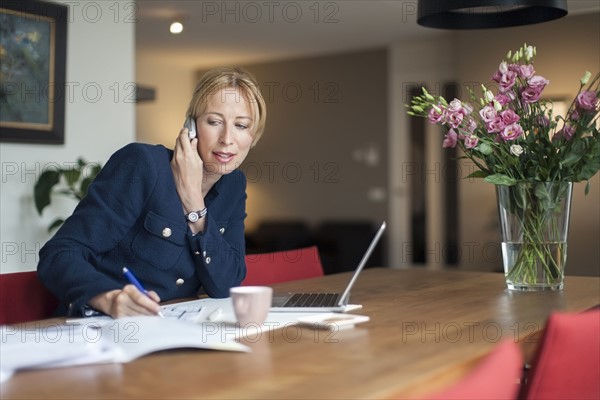 Woman talking on phone and making notes