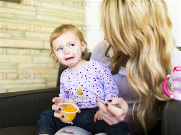 Woman feeding her daughter (12-17 months)