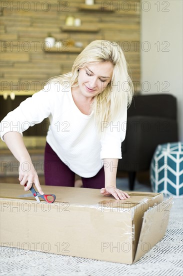 Young woman opening box with scissors