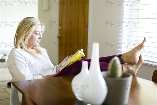 Young woman reading book at table