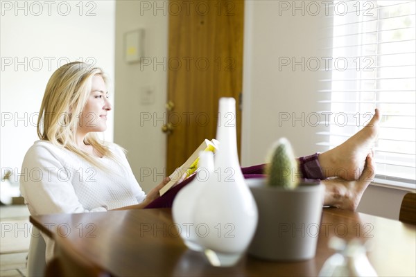 Young woman reading book at table