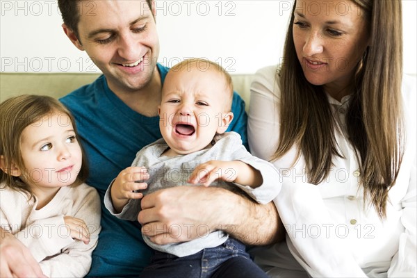 Family with two children (2-3, 4-5) sitting on sofa