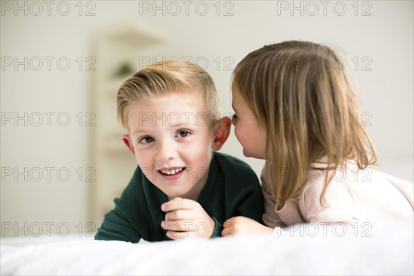 Siblings (2-3, 4-5) whispering in bedroom
