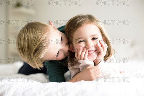 Siblings (2-3, 4-5) whispering in bedroom