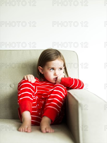 Girl (4-5) in pajamas sitting on sofa