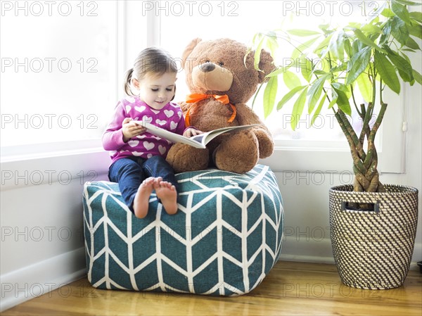 Girl (4-5) sitting with teddy bear on bean bag