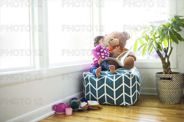 Girl (4-5) kissing her teddy bear on bean bag