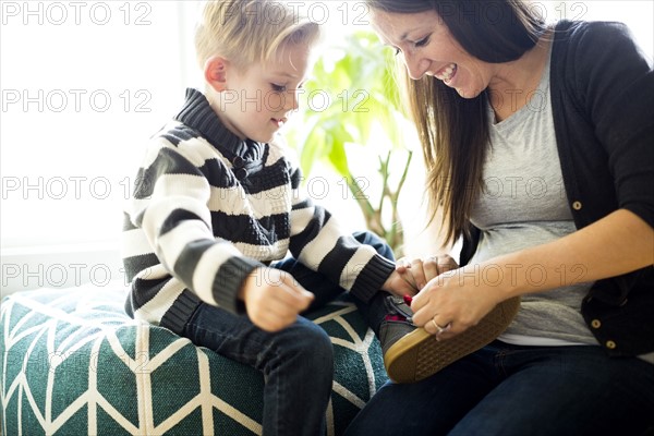 Mother helping son (6-7) putting shoe on