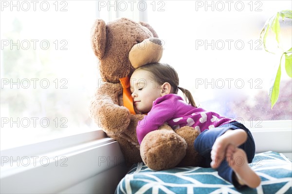 Girl (4-5) embracing teddy bear