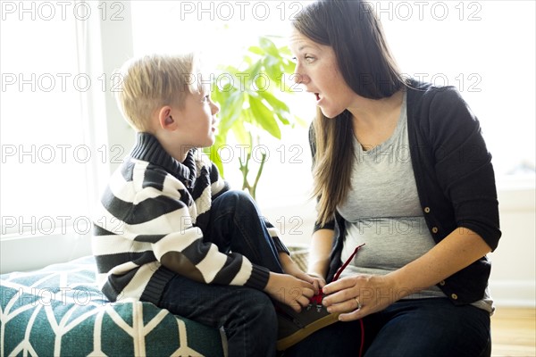 Mother helping son (6-7) putting shoe on