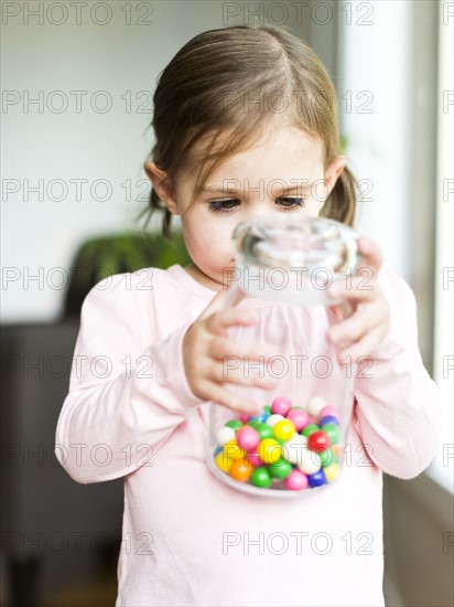Girl (4-5) holding glass jar with candies