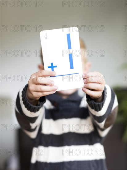 Boy (6-7) holding math card