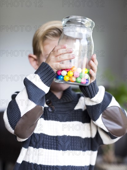 Boy (6-7) holding glass jar with candies