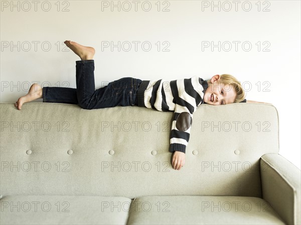 Boy (6-7) lying on sofa