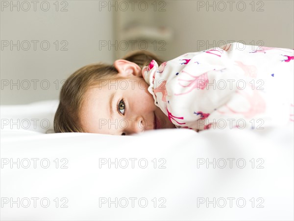 Girl (2-3) lying on bed