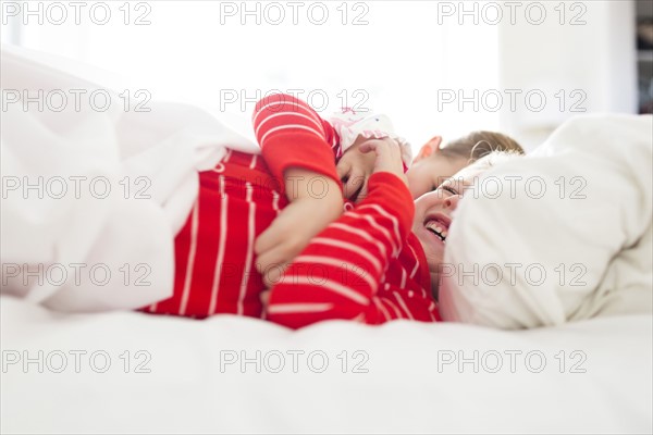 Brother (6-7) and sister (4-5) laughing in bed
