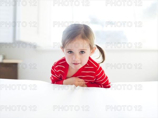 Girl (4-5) leaning on bed