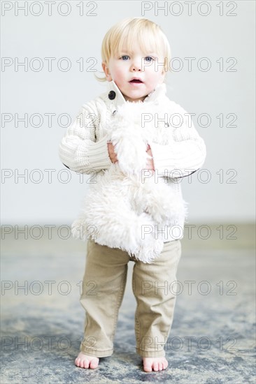 Boy (2-3) holding toy dog standing on floor