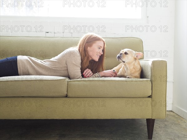 Woman and pug lying on sofa