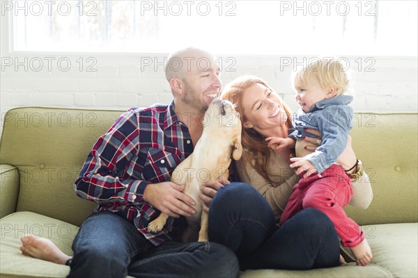 Family with son (2-3) and pug on sofa