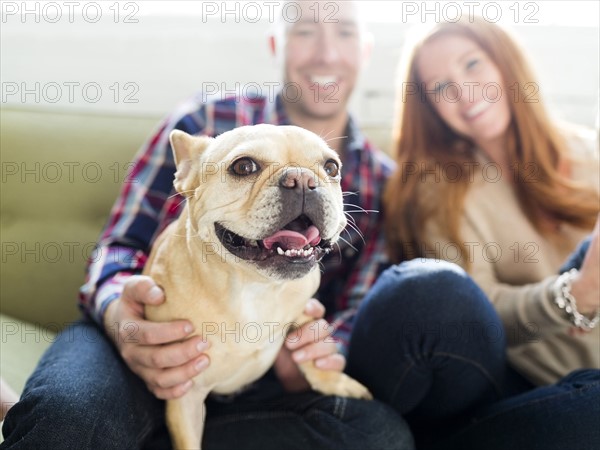 Couple with pug sitting on sofa