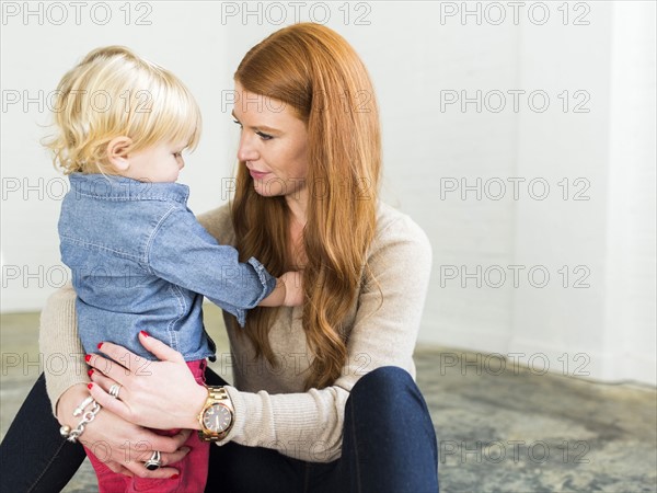 Mother sitting on floor embracing boy (2-3)