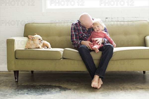Father sitting on sofa embracing baby son (2-3)
