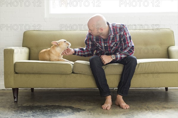 Man sitting on sofa stroking pug