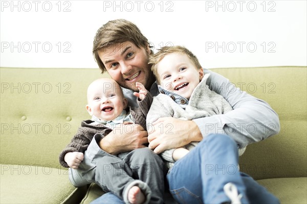 Father embracing two sons (6-11 months and 2-3 years)