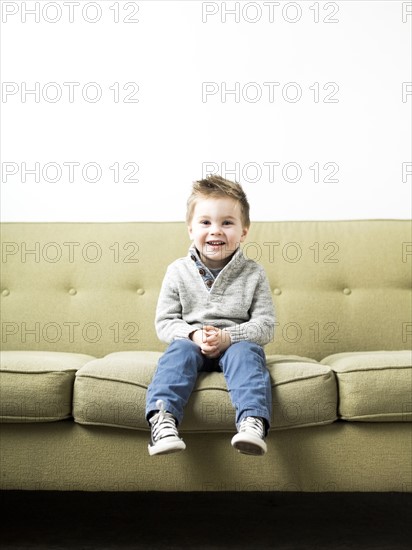 Baby boy (2-3) sitting on sofa