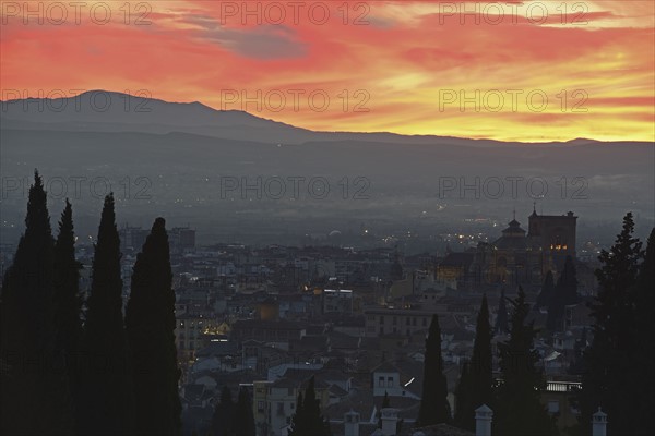 Cityscape and hill at sunset, red yellow sky