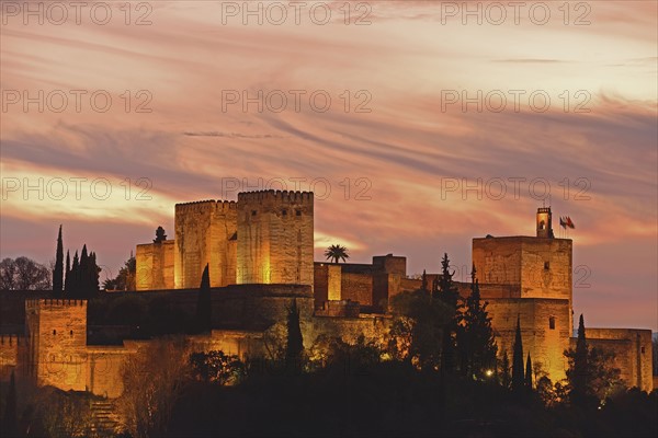 Illuminated castle at dusk, pastel colored clouds in sky