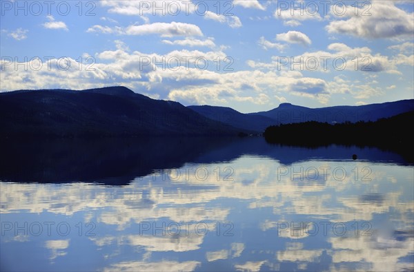 Symmetrical view of blue sky and clouds reflecting in lake