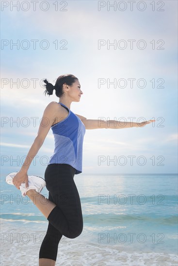 Young woman exercising by sea.