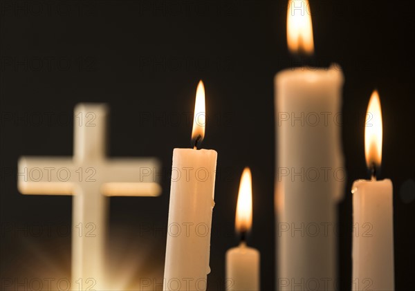 Burning candles with cross in background.