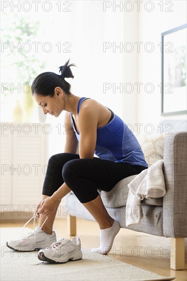 Young woman putting on shoes.