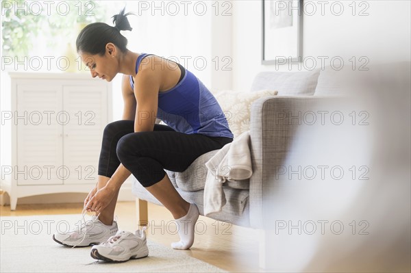 Young woman putting on shoes.