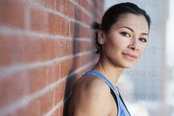 Portrait of young woman by brick wall.