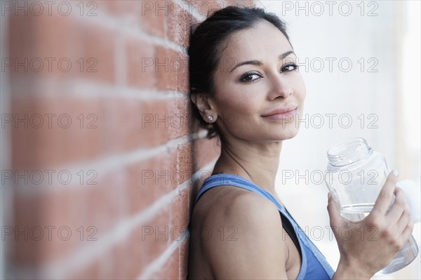 Portrait of young woman by brick wall.