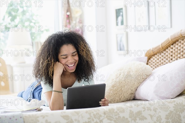 Teenage girl (16-17) using tablet pc in bedroom.