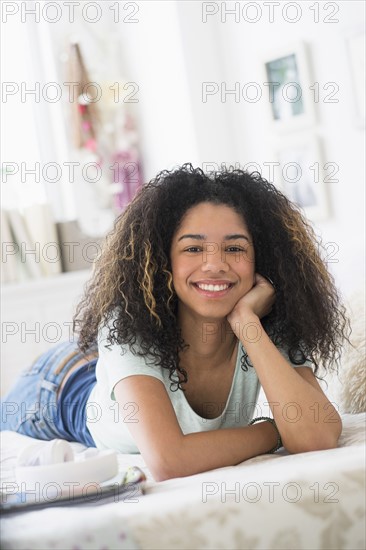 Portrait of teenage girl (16-17) lying on bed.