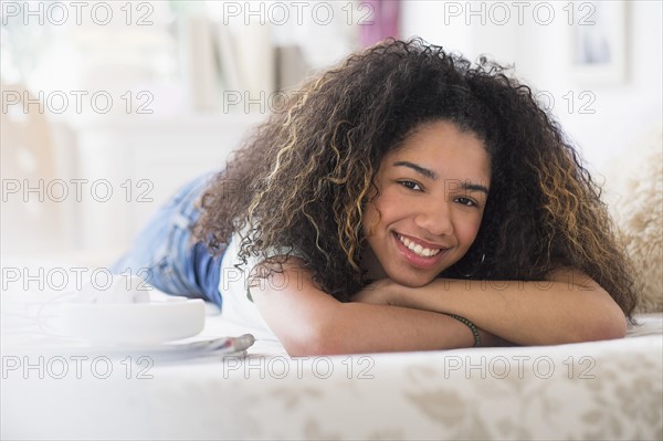 Portrait of teenage girl (16-17) lying on bed.