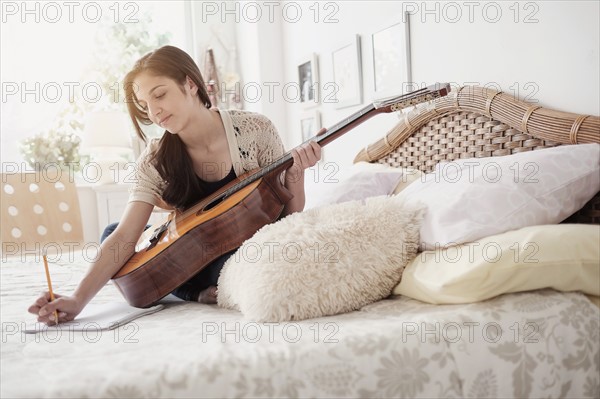 Teenage girl (14-15) playing guitar.