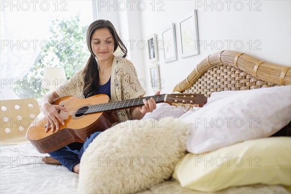 Teenage girl (14-15) playing guitar.