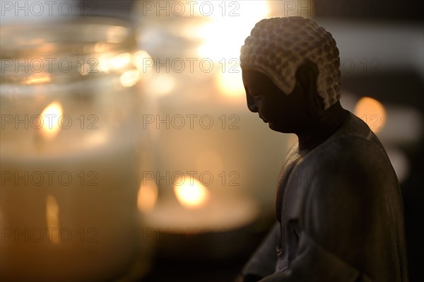 Burning candles with Buddha figurine in foreground.