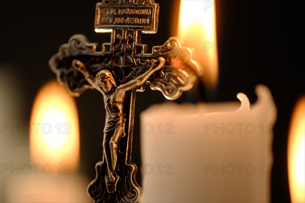 Burning candles and cross .