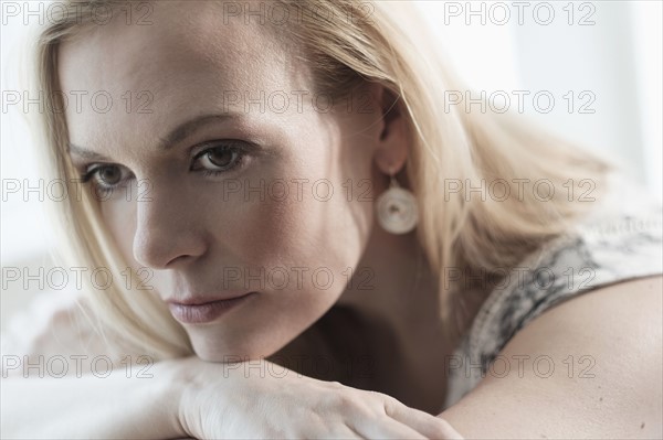 Pensive mid-adult woman lying on bed.